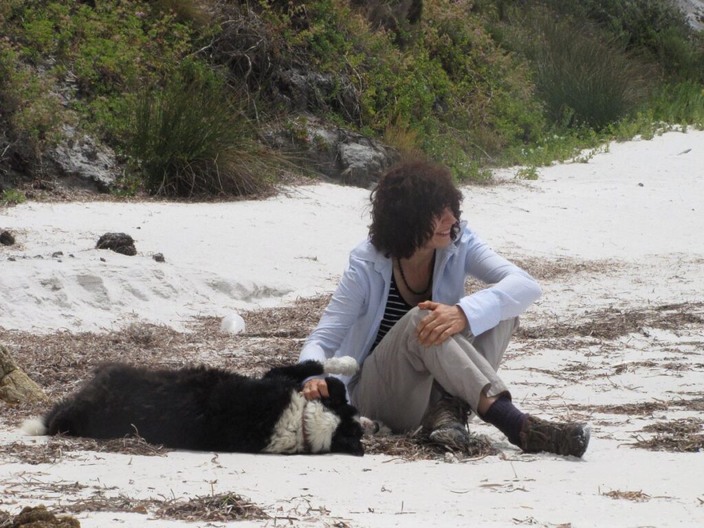 Ältere Frau geht mit ihrem Hund am Strand spazieren