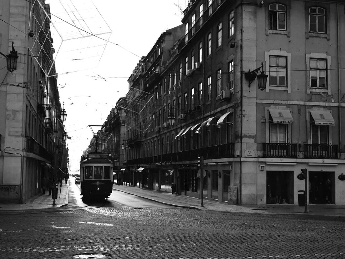 Historische Straßenbahn fährt durch eine enge Altstadtgasse in Lissabon