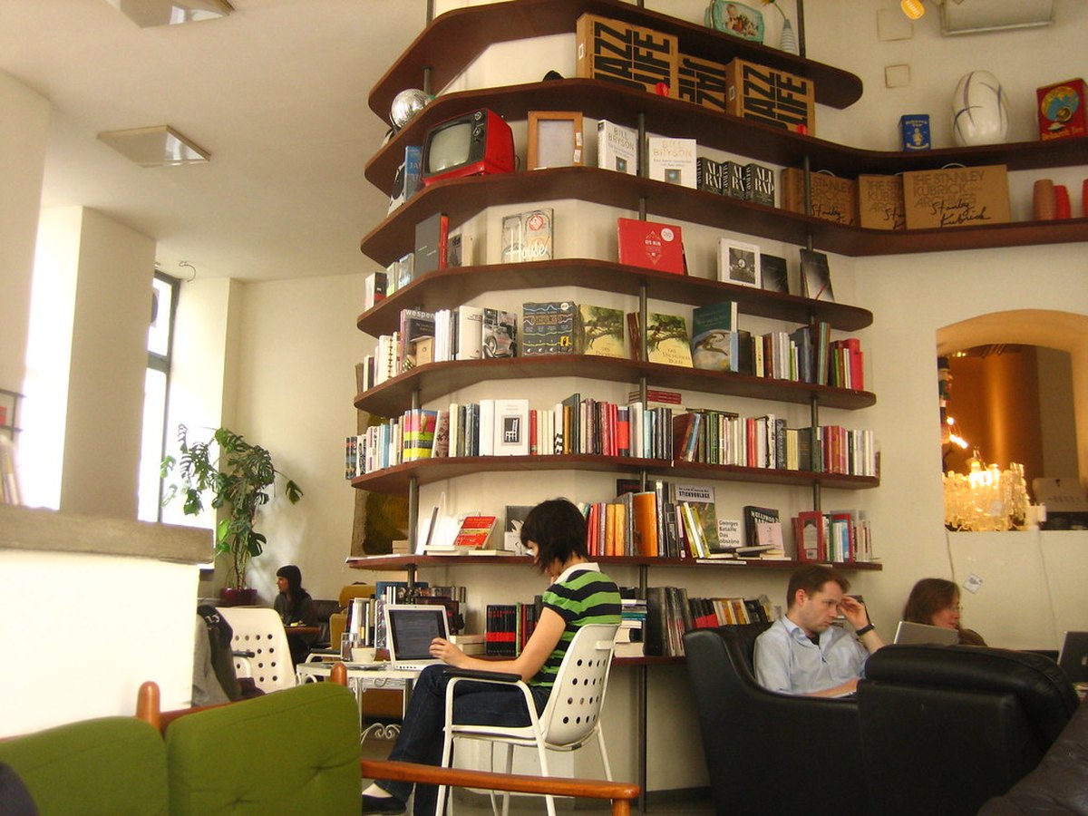 Gäste sitzen in einem gemütlichen Wiener Kaffeehaus mit Bücherregalen an der Wand