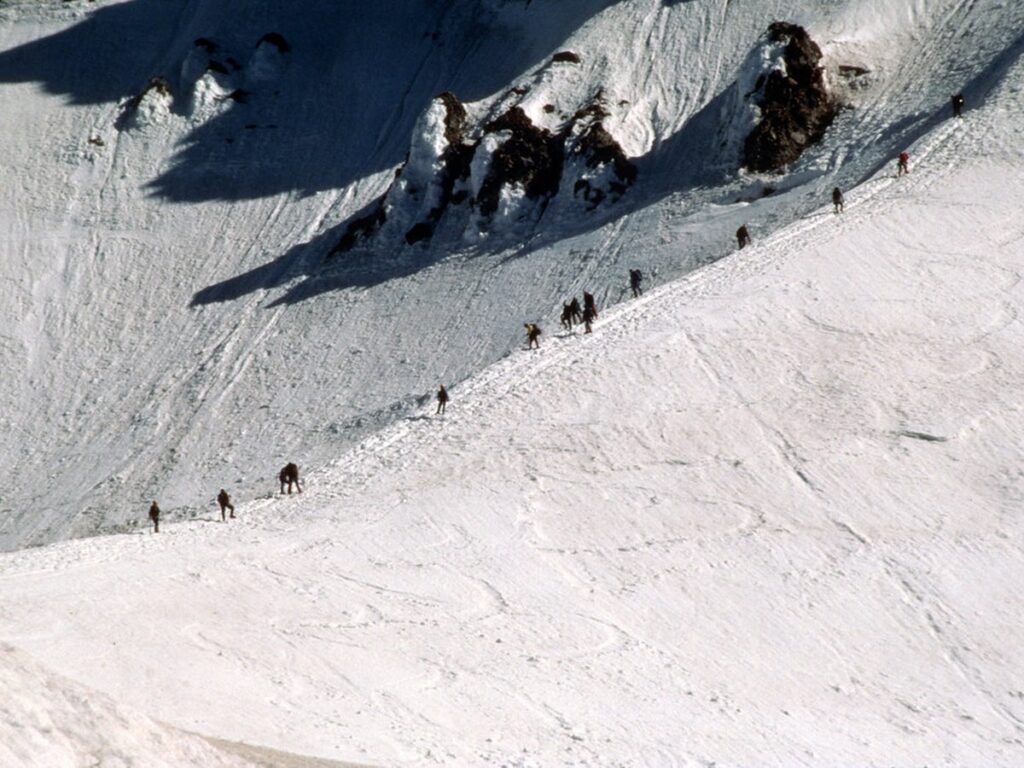 Wandergruppe im Gänsemarsch beim Aufstieg über einen schneebedeckten Berghang